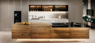 Le ante delle basi dell'isola della cucina 36e8 Cut di LAGO sono caratterizzate da un'apertura a gola che non interrompe l'uniformità della superficie in legno con venature a vista. A parete trovano posto le basi nella finitura marmo con la zona lavaggio, le colonne e i pensili a sviluppo orizzontale in vetro fumé. Prezzo su richiesta. https://www.lago.it