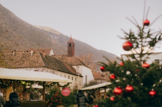 Polvere di Stelle è il mercatino di Natale di Lana che si svolge nel Giardino dei Cappuccini i fine settimana dal 28 novembre al 31 dicembre 2025. Tra le 22 bancarelle addobbate a festa contadini, artigiani e creativi presentano una selezione di tanti oggetti fatti a mano: bigiotteria, vestiti ecologici, oggetti in legno tornito, addobbi natalizi, lanterne di carta e manufatti in ceramica. Come ogni anno è presente la ragazza che rappresenta l’orfana, protagonista della fiaba dei fratelli Grimm, Pioggia di Stelle, con i biglietti della fortuna che danno la possibilità di vincere premi e, allo stesso tempo, di portare speranza a chi è in difficoltà. Foto: Tobias Kaser. www.merano-suedtirol.it/it/natale-a-lana.html