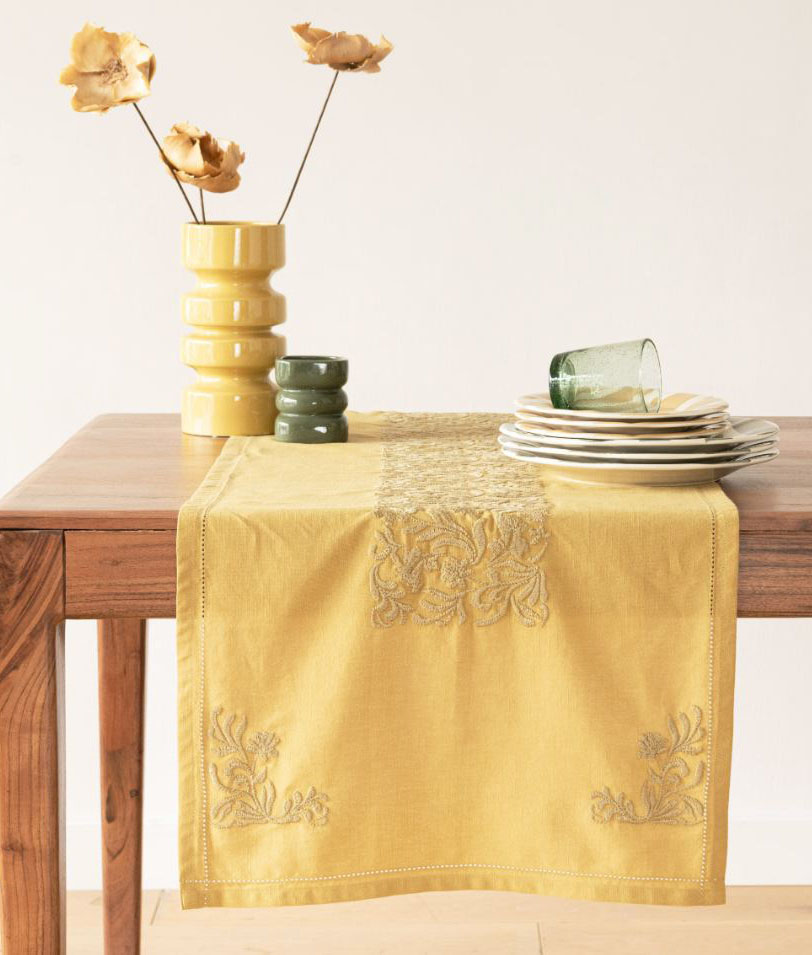 Morbido cotone giallo per il runner Andrea di Maisons du Monde che è impreziosito da una serie di ricami floreali, tono su tono, posizionati agli angoli e al centro. Lo stile bohémien permette di  accostarlo ad arredi e stoviglie contemporanei. Misura L 50 x P 150 cm. Prezzo 25,99 euro. https://www.maisonsdumonde.com