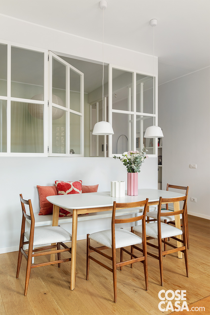 zona pranzo con tavolo bianco sedie e panca