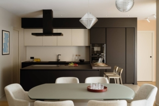 Cucina a vista sul living arredata con una composizione che unisce toni scuri e toni chiari