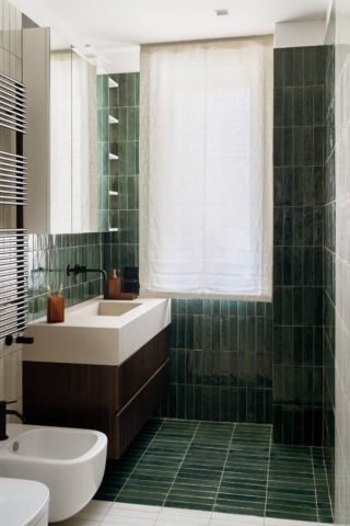 Bagno con vasca, rivestito con piastrelle verdi e bianche