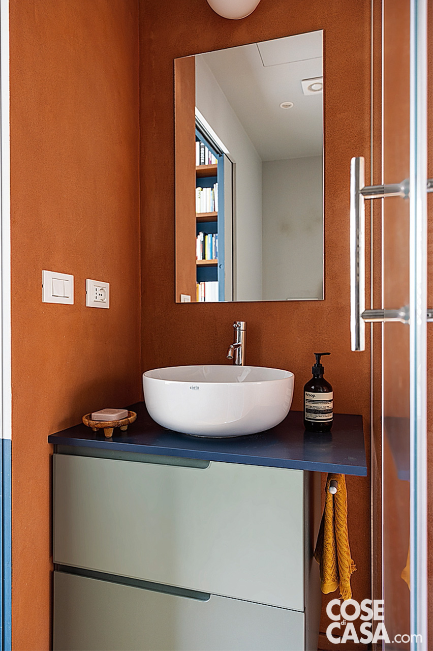 bagno con lavabo tondo mobile blu e parete terracotta