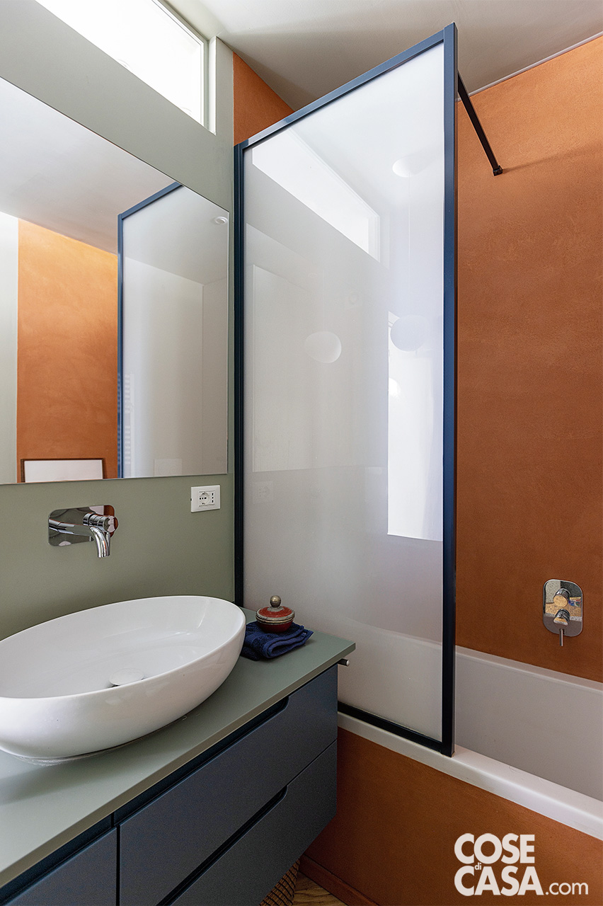 bagno con vasca mobile blu e parete terracotta