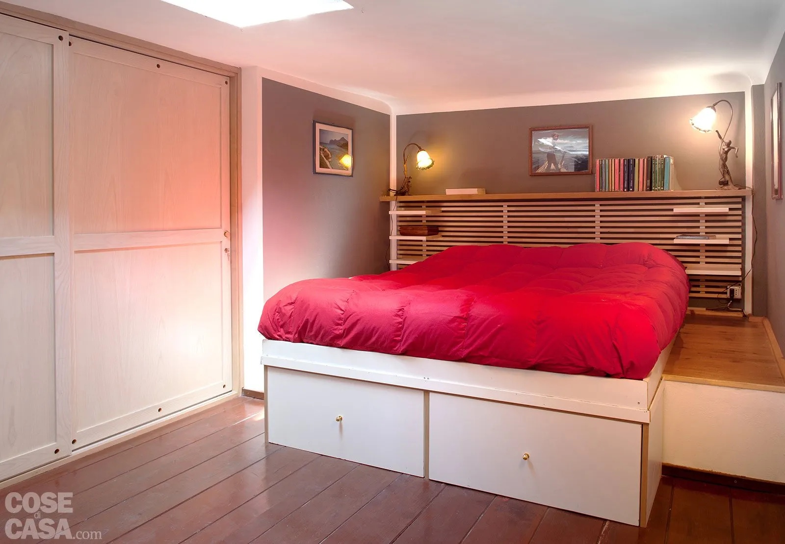 In questa camera da letto matrimoniale, posizionata su un soppalco, il pavimento è in doghe di legno color mogano. In abbinamento troviamo il bianco del mobile e della pedana con cassettoni e la tinta terra delle pareti che circondano il letto, che nell'insieme dà un effetto di naturalezza e semplicità. A dare un tocco di colore è stato scelto un piumone copriletto di tonalità rosso acceso che spezza l'uniformità.
Progetto d’arredo arch. Ornella Budetta Milano, Tel. 02/6695043, o.budetta@tiscalit.it con Bruno Salera - Foto Cristina Fiorentini