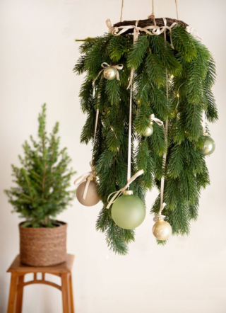 Una corona di pino cadente in materiale sintetico PE, appesa al soffitto, può essere una valida alternativa all'abete tradizionale. Misura Ø 110 cm. Prezzo 29,90 euro. È decorata con palline, grandi e piccole, nelle delicate tonalità verde e beige, sospese per mezzo di nastrini colorati. Tutto in vendita nei Viridea Garden Center. https://shop.viridea.it