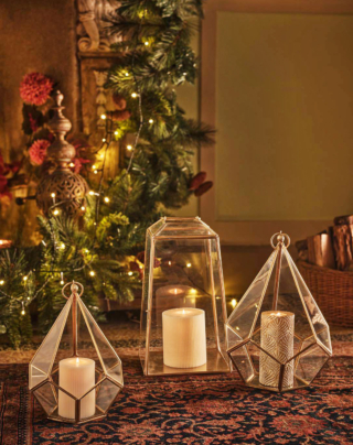 Hanno dimensioni importanti le lanterne portacandela di Coincasa con il sottile telaio in ottone dorato e vetro trasparente. Grazie al gancio possono essere appese oppure poggiate direttamente a terra, magari ai piedi dell'albero di Natale. Il modello squadrato misura H 34 cm. Prezzo 59,90 euro.  La variante a punta misura H 25 cm e H 33 cm. Prezzo 39,90 euro.  https://www.coin.it/