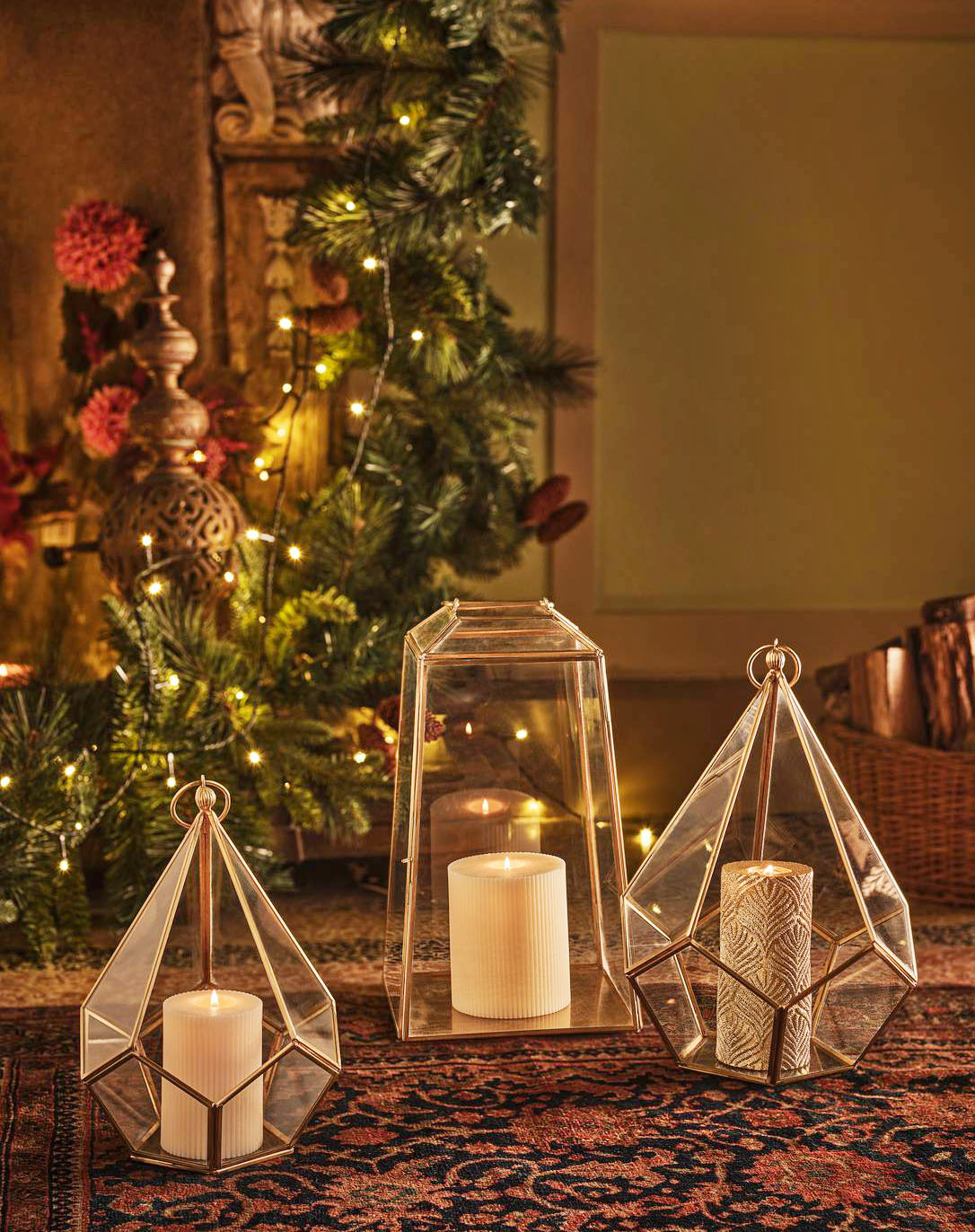 Hanno dimensioni importanti le lanterne portacandela di Coincasa con il sottile telaio in ottone dorato e vetro trasparente. Grazie al gancio possono essere appese oppure poggiate direttamente a terra, magari ai piedi dell'albero di Natale. Il modello squadrato misura H 34 cm. Prezzo 59,90 euro.  La variante a punta misura H 25 cm e H 33 cm. Prezzo 39,90 euro.  https://www.coin.it/