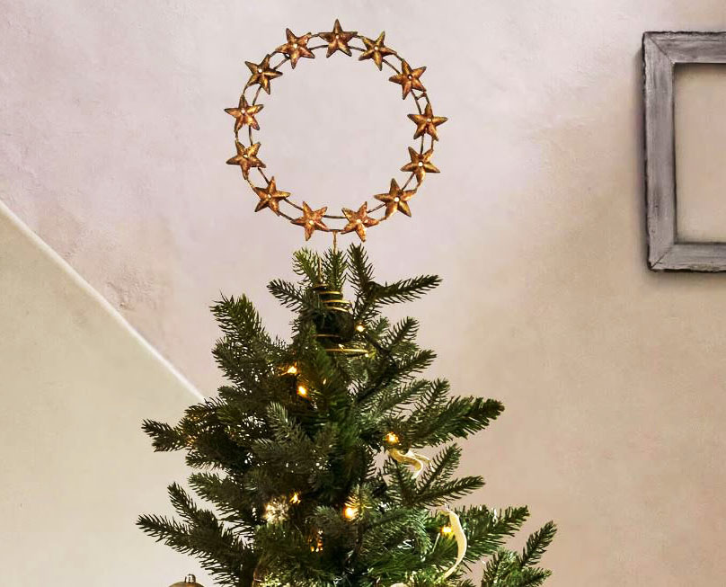 Una corona di stelline dorate per il puntale dal fascino vintage Tavelle di Loberon che è caratterizzato da una sottile struttura in ferro con una raffinata colorazione oro antico. È impreziosita da piccole perline posizionate al centro di ogni stella. Misura Ø 29 x H 29 cm. Prezzo 19,95 euro. https://www.loberon.it