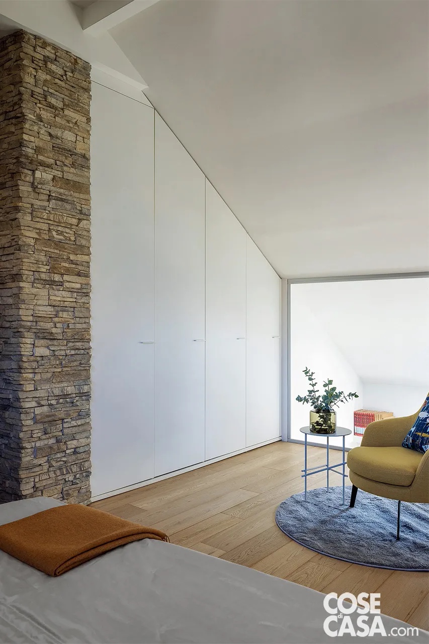 È il caso di questa camera matrimoniale che si affaccia sul soggiorno a doppia altezza tramite una vetrata. Qui è stato realizzato un armadio su disegno, in laccato bianco opaco, che risolve anche la presenza di un pilastro portante, valorizzato dal rivestimento in pietra, e che presenta ante ad altezza differenziata.
Progetto: Studio ARCHISPRITZ, arch. Patrizia Vaccaro e arch. Annalisa Barbera Fortuna, None (TO) e Biella - https://www.archispritz.com - Foto: Cristina Galliena Bohman - Styling: Laura Mauceri