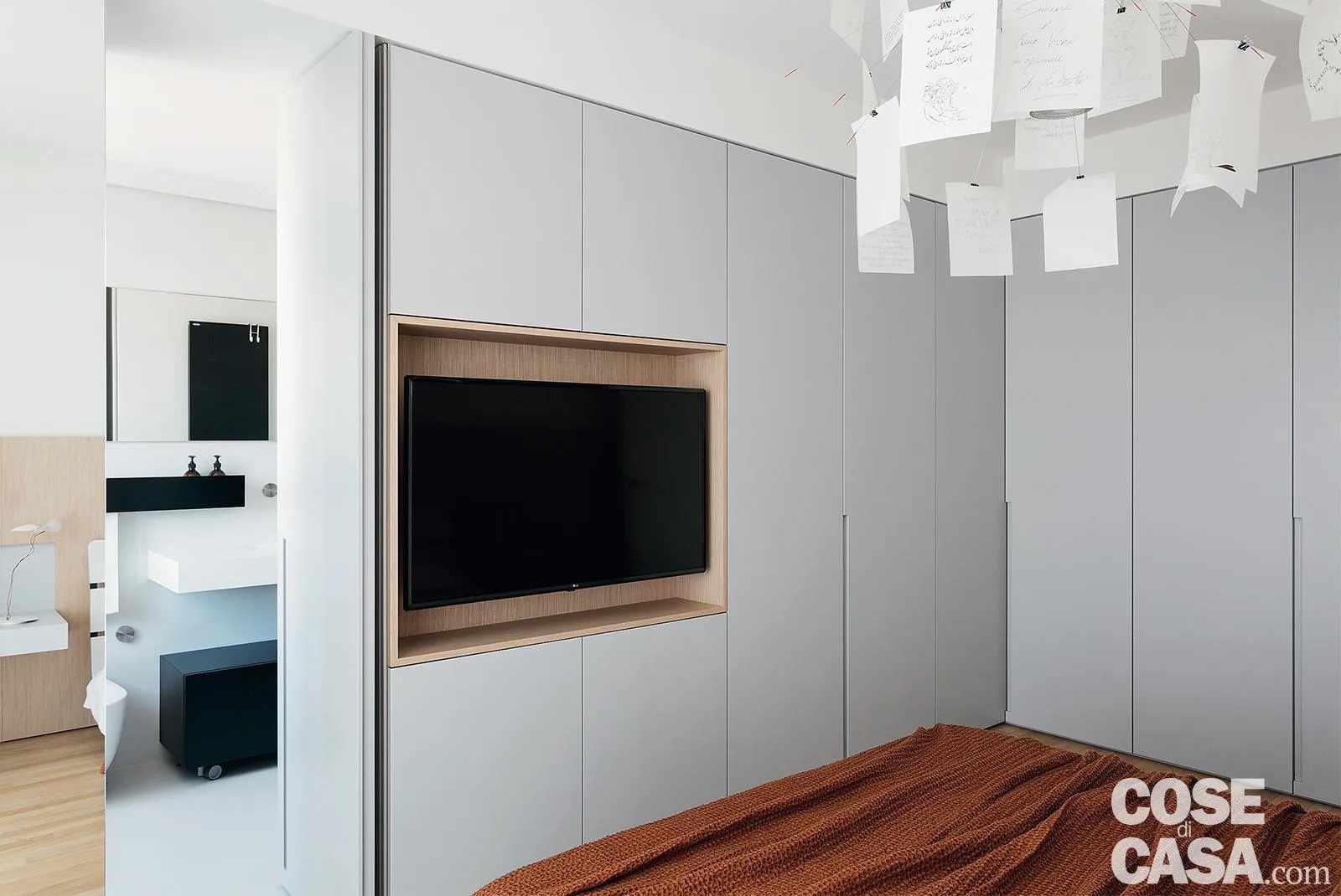 In questa stanza è stato inserito un armadio angolare su misura, in finitura laccato grigio chiaro, tamponato in alto con cartongesso. Il mobile, molto semplice e lineare, comprende uno spazio per il televisore e la porta del bagno a uso esclusivo, realizzata nella stessa finitura: l'insieme dà un effetto di uniformità ed essenzialità.
Progetto: arch. Ezio Zupelli, ZDA-Zupelli Design Architettura, Orzinuovi (Bs), Tel. 030/5243585 - https://www.zupellidesignarchitettura.com - Foto: Studio Roy - Styling: Lidia Elisa Covello