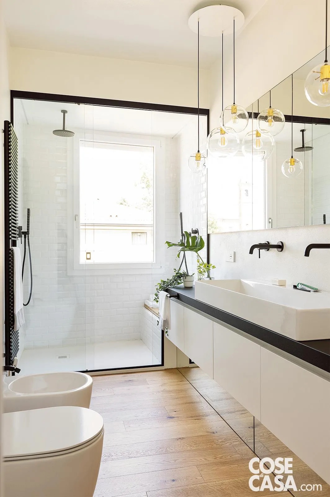 È il caso di queste lampade a sospensione fissate a soffitto tramite una piattaforma rotonda, da cui pendono dei semplici bulbi chiusi in sfere trasparenti. Si inseriscono perfettamente in un ambiente caratterizzato dal contrasto black and white, dove alla prevalenza del bianco fanno da contraltare delle finiture nere, utilizzate per la rubinetteria, lo scaldasalviette, il piano del mobile e i profili della doccia, che rendono lo stile del bagno molto contemporaneo.
Progetto: atelierXS martina gualdi laura provasi architetti, Carpi (Mo), Tel. 059/650031 https://www.atelierxs.com - Foto: Cristina Galliena Bohman - Styling: Laura Mauceri