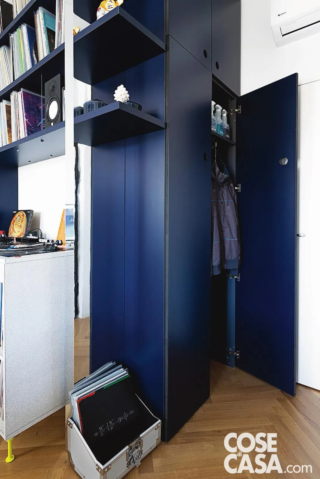 Il mobile su misura in MDF, rivestito in laminato blu navy, ingloba il tramezzo esistente e un pilastro strutturale, integrando il passaggio verso la camera tramite una doppia porta basculante “a saloon”. I vani chiusi, profondi circa 35 cm, seguono il profilo del varco e diventano ripostigli verticali. Il mobile su misura in MDF, rivestito in laminato blu navy, ingloba il tramezzo esistente e un pilastro strutturale, integrando il passaggio verso la camera tramite una doppia porta basculante “a saloon”. I vani chiusi, profondi circa 35 cm, seguono il profilo del varco e diventano ripostigli verticali.