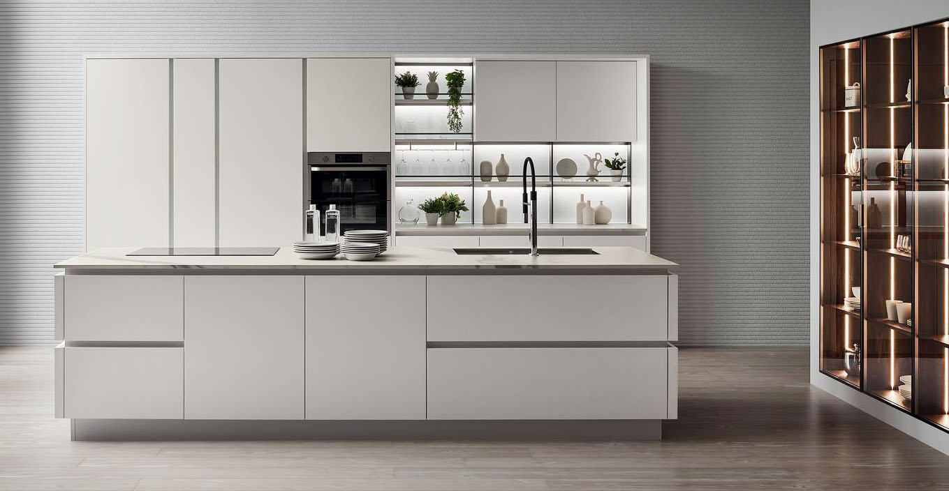 Effetto total white per Oyster di Veneta Cucine che si compone di una grande isola centrale attrezzata con lavello e piano cottura a induzione e di una armadiatura a parete con colonne che accolgono gli elettrodomestici e la dispensa. Le ante lisce sono realizzate in Laccato Opaco Bianco Puro con il sistema apertura ShellSystem; il top è in Caranto Ker nella finitura Calacatta Statuario Opaco. Prezzo su richiesta. https://www.venetacucine.com