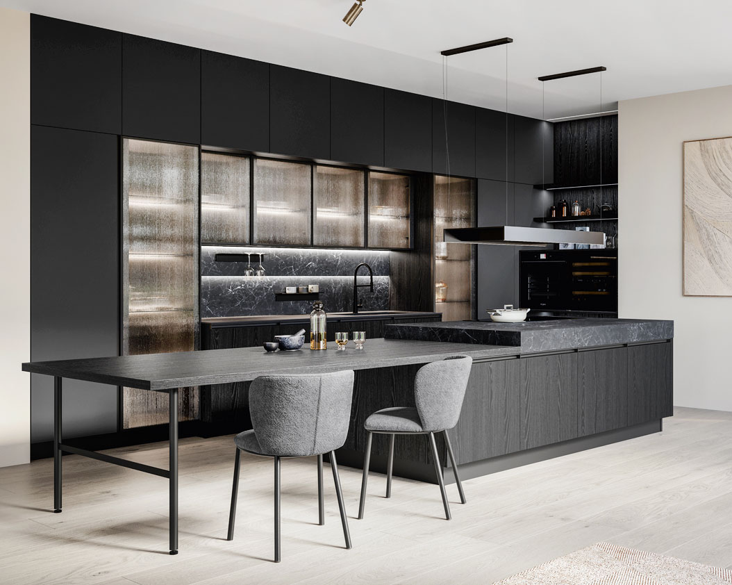 Si apre completamente sulla zona giorno la cucina Kalì di Arredo3 che è dominata dalla grande isola dotata di tavolo da pranzo con l’elegante struttura a ponte. Le ante delle basi sono in Laminato Rovere Fumé, i pensili e le colonne sono in Pet riciclato Stromboli. La zona lavaggio a parete è incorniciata da colonne e pensili con ante Teca in vetro millerighe e ripiani in vetro completati dalle luci a Led Back. Il Laminam Nero Greco dei piani di lavoro è ripreso dallo schienale Duetto attrezzabile con gli accessori magnetici Origami e dotato di illuminazione. Prezzo su richiesta. https://www.arredo3.com