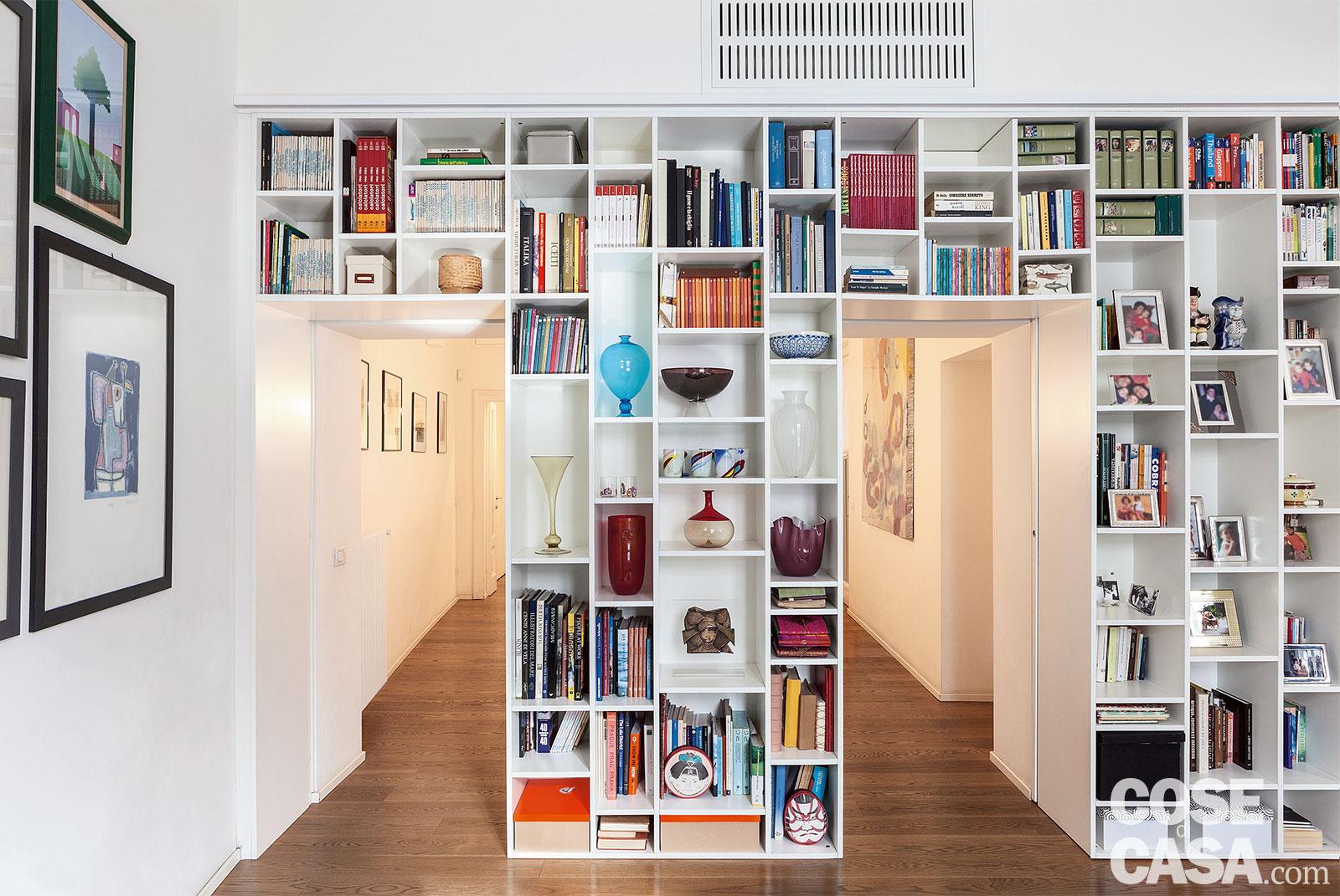 Libreria realizzata per recuperare spazio perso a causa del corridoio. Presenta due vani di passaggio con porte scorrevoli di falegnameria, una soluzione a tutta altezza, che presenta un tamponamento per raggiungere i 3 metri di altezza del soffitto e gli split del climatizzatore. Progetto: arch. Raffaele Azzarelli e Giuliano Iamele; Foto: Claudio Tajoli; Styling: Rosaria Galli. Libreria realizzata per recuperare spazio perso a causa del corridoio. Presenta due vani di passaggio con porte scorrevoli di falegnameria, una soluzione a tutta altezza, che presenta un tamponamento per raggiungere i 3 metri di altezza del soffitto e gli split del climatizzatore. Progetto: arch. Raffaele Azzarelli e Giuliano Iamele; Foto: Claudio Tajoli; Styling: Rosaria Galli.