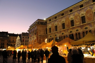 Una scintillante coreografia dorata grazie al videomapping Faber Aura "L’Oro e le Stelle" di piazza dei Signori illumina il mercatino di Natale nell’adiacente piazza Biade a Vicenza. Il mercatino di Natale si snoda anche in piazza San Lorenzo, poco lontano, sempre nel cuore della città che nel 1994 è stata riconosciuta, insieme alle Ville del Palladio, sito patrimonio mondiale dell’Umanità da parte dell’UNESCO. Ai mercatini si possono acquistare svariati oggetti di artigianato e prelibate specialità locali nonché trovare tante idee regalo. Fino al 4 gennaio 2026. Dal 6 all’8 dicembre 2025 si svolge in piazza dei Signori “Unico”, il mercato del fatto a mano in versione natalizia. Foto: Vicenza è. www.vicenzae.org Una scintillante coreografia dorata grazie al videomapping Faber Aura "L’Oro e le Stelle" di piazza dei Signori illumina il mercatino di Natale nell’adiacente piazza Biade a Vicenza. Il mercatino di Natale si snoda anche in piazza San Lorenzo, poco lontano, sempre nel cuore della città che nel 1994 è stata riconosciuta, insieme alle Ville del Palladio, sito patrimonio mondiale dell’Umanità da parte dell’UNESCO. Ai mercatini si possono acquistare svariati oggetti di artigianato e prelibate specialità locali nonché trovare tante idee regalo. Fino al 4 gennaio 2026. Dal 6 all’8 dicembre 2025 si svolge in piazza dei Signori “Unico”, il mercato del fatto a mano in versione natalizia. Foto: Vicenza è. www.vicenzae.org