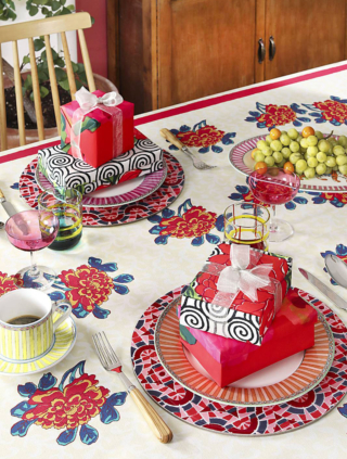 Allegra e originale la tavola delle feste di Lisa Corti che abbina i piatti in porcellana del servizio Sariska Pink Unica e Orange al telo in cotone Ortensia Red Gold usato come tovaglia. I bicchieri colorati riprendono i colori delle stoviglie. Il set di 3 piatti Sariska prezzo 75 euro. Il telo Ortensia Red Gold misura L 180 x P 350 cm, prezzo 255 euro. I piccoli pacchetti posati sui piatti fungono da segnaposto e da decorazione.  https://www.lisacorti.com