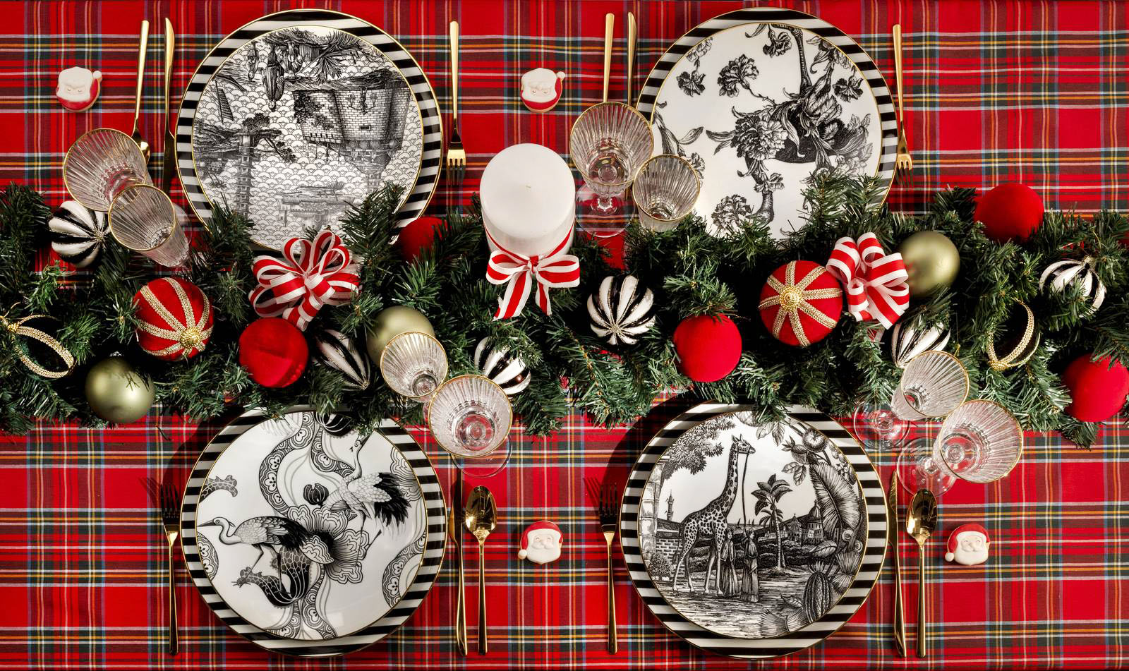 Stile mix and match per la tavola di Natale di Weissestal che abbina i piatti della collezione Souvenirs de Voyage, decorati da scene in bianco e nero ispirate al passato, alla tovaglia scozzese rosso e verde. I piatti sono prodotti in porcellana rifinita a mano con un filo in vero oro. Il piatto piano misura Ø 27,5 cm, prezzo 60 euro. Il centrotavola è composto da una ghirlanda di pino con palline e fiocchetti. https://www.weissestal.it