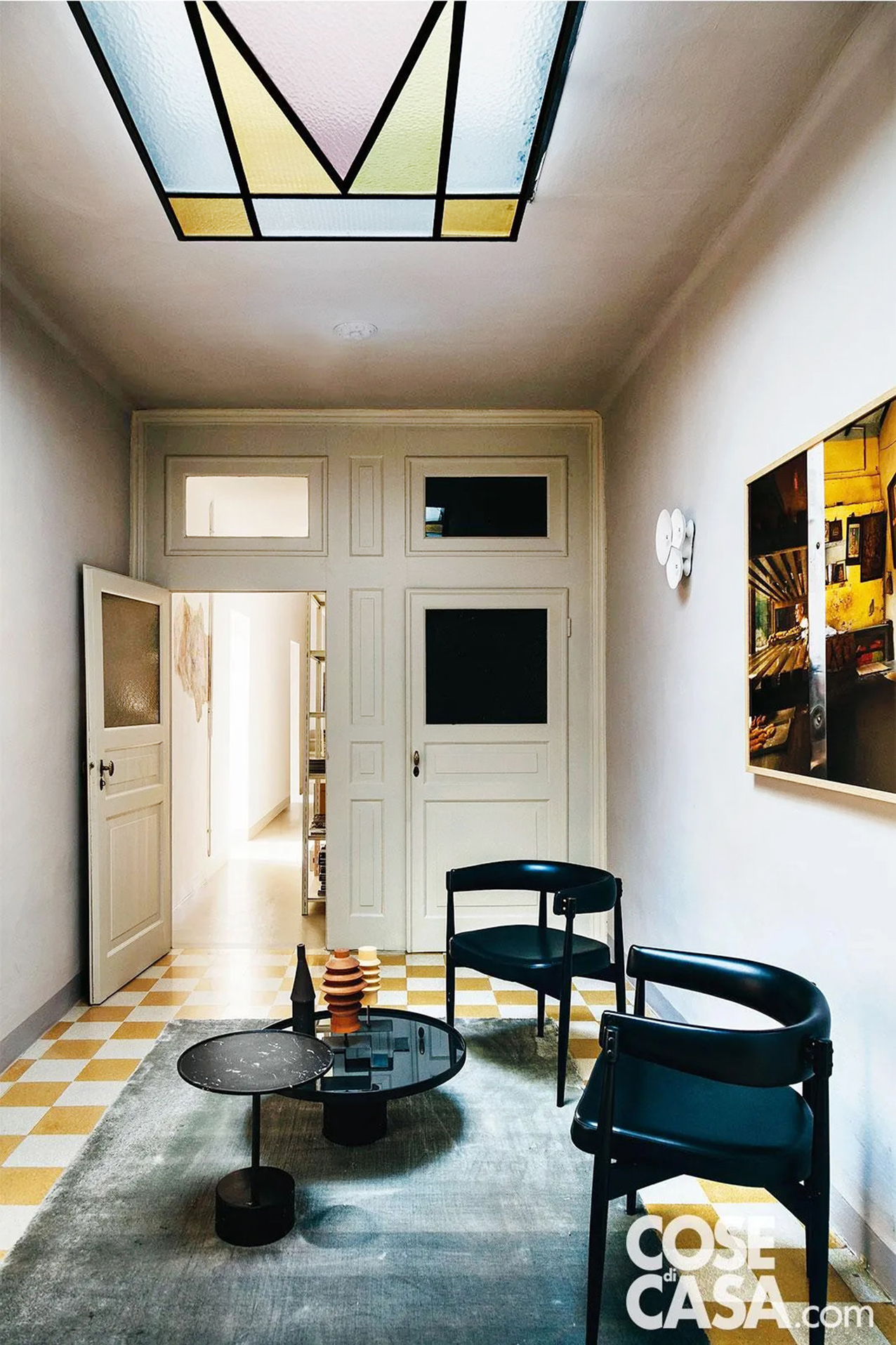 In questo appartamento, che funge allo stesso tempo da casa e studio professionale, l'ingresso presenta elementi strutturali originali che sono stati mantenuti, quali il lucernario con vetri colorati, il pavimento a scacchiera in marmette, le porte bianche con inserti a vetro.
Questo locale da semplice ambiente di passaggio è stato trasformato in un piccolo salotto, accostando ai materiali e ai colori esistenti degli elementi di colore nero a creare un forte contrasto e in stile moderno, con tavolini rotondi di produzione e poltroncine vintage.
Progetto: Arch. Pierluigi Molteni, Bologna Tel. 051/5542090 https://www.pierluigimolteni.it - Foto: Lea Anouchinsky