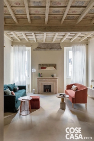 In questa abitazione vincolata dalla Soprintendenza, l'area conversazione presenta un soffitto in laterizio e legno con riquadri affrescati, con disegni nei toni dell'azzurro e del rosa, di grande raffinatezza. I due divani moderni, posti l'uno di fronte all'altro, sono realizzati in stili diversi e in due tonalità, bluette e rosa intenso, che richiamano i decori antichi del soffitto e sono affiancati da tavolini, lampade e pouf dai colori tenui, terracotta, crema, rosa, e dalle forme attuali. A terra è stata posata una pavimentazione in resina bianca dal gusto estremamente contemporaneo.
Progetto: arch. Ilaria Bellia, Bstudio Roma, Tel. 06/89014876 https://www.bstudio-arch.com ilaria.bellia@bstudio-arch.com hello@bstudio-arch.com - Foto: Studio Wolo