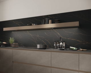La cucina punta sull’eleganza: il top e lo schienale
in HPL Oro Nero si armonizzano con le ante
Malta Ombra. La cappa Shelf, con frontale
personalizzato in bronzo millerighe, riprende le
tonalità bronzate della gola e dello zoccolo. Gli
effetti metallici sono di grande tendenza.Top e schienale in HPL Oro Nero, ante in laminato Malta Ombra e cappa Shelf in bronzo millerighe