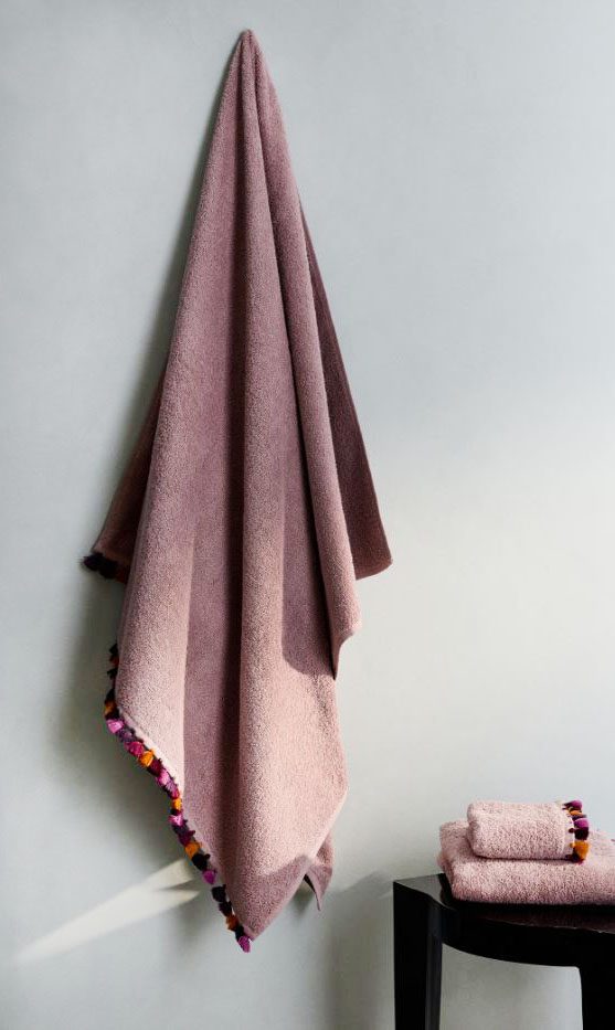 Hanno il bordo decorato da piccoli pon pon colorati gli asciugamani di Mango in spugna di puro cotone color Lavanda. Sono disponibili nelle versioni da bagno, lavabo e toletta. Misurano L 90 x P 150 cm, L 50 x P 90 cm e L 30 x P 50 cm. Prezzo a partire da 7,99 euro. https://shop.mango.com