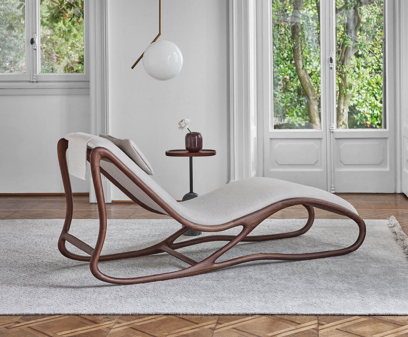 La chaise longue Twilli di Porada abbina una sinuosa struttura in pregiato legno massello di noce canaletta a una seduta rivestita in tessuto chiaro; è sfoderabile. È presente un comodo cuscinetto poggiatesta adattabile. Misura L 70 x P 185 x H 86 cm. Prezzo su richiesta. https://www.porada.it