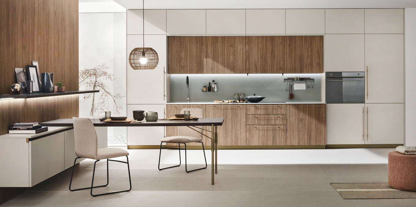 La venatura del Noce Eucalipto impreziosisce le ante delle basi e dei pensili nella cucina Metropolis di Stosa; le colonne e i pensili a sviluppo orizzontale hanno le ante in Pet Cachemere opaco che danno vita ad un raffinato contrasto. Il top è realizzato in pietra Neolith Calacatta Silk; le grandi maniglie godronate sono in metallo nella finitura Bronzo come le gambe del tavolo con il piano in fenix Cacao Orinoco. https://www.stosacucine.com