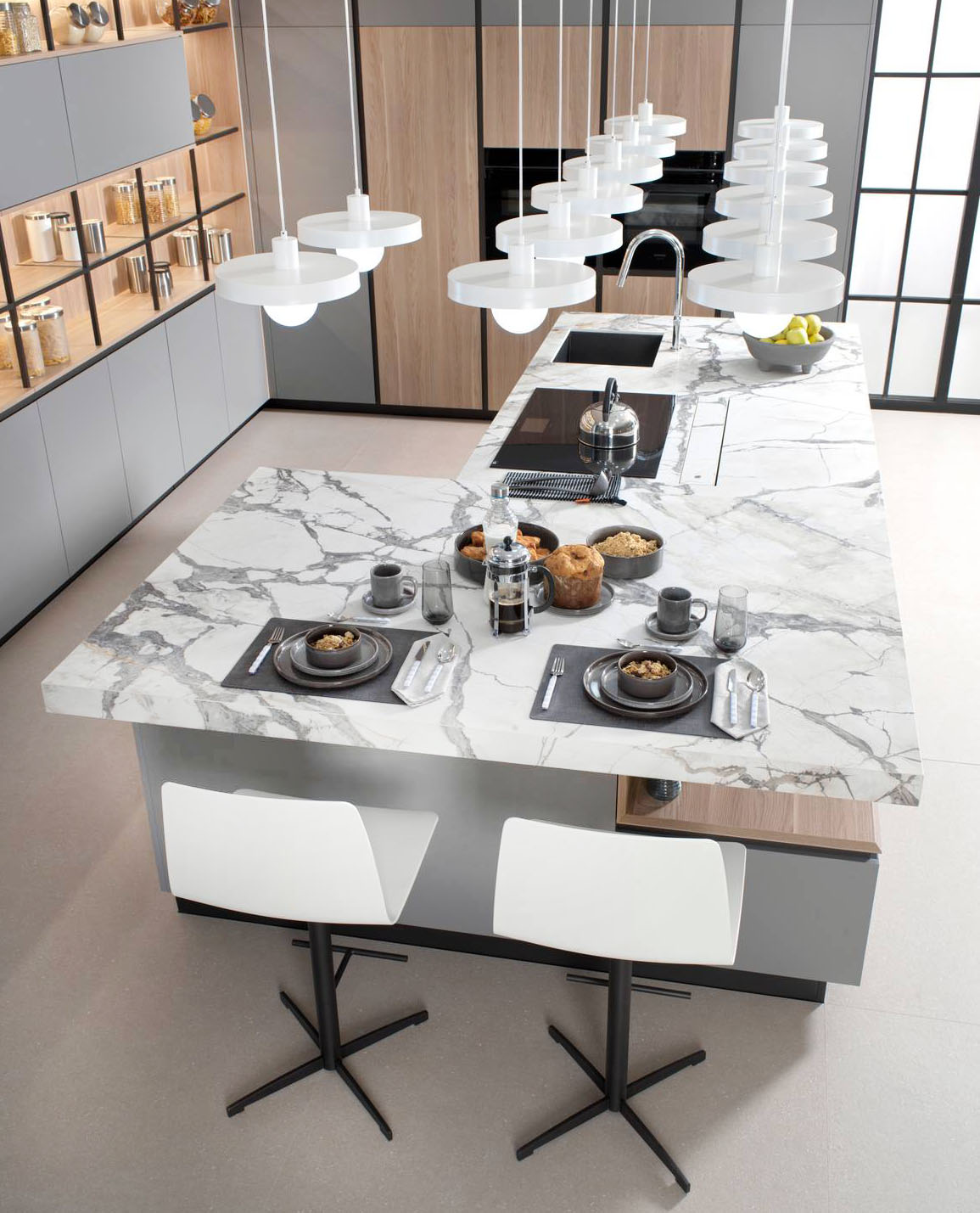 Permette di consumare i pasti e cucinare contemporaneamente l'ampia isola attrezzata che domina la cucina R1.90 Clear – R3.90 Wind Mate di Porcelanosa e che ha il piano di lavoro realizzato in ceramica di grande formato Xtone Invisible White con finitura Nature che integra il piano cottura, il lavello e il bancone per la colazione a sbalzo. L'armadiatura a parete è composta da colonne con i ripiani in legno e i frontali Wind Mate. Prezzo su richiesta. https://www.porcelanosa.com