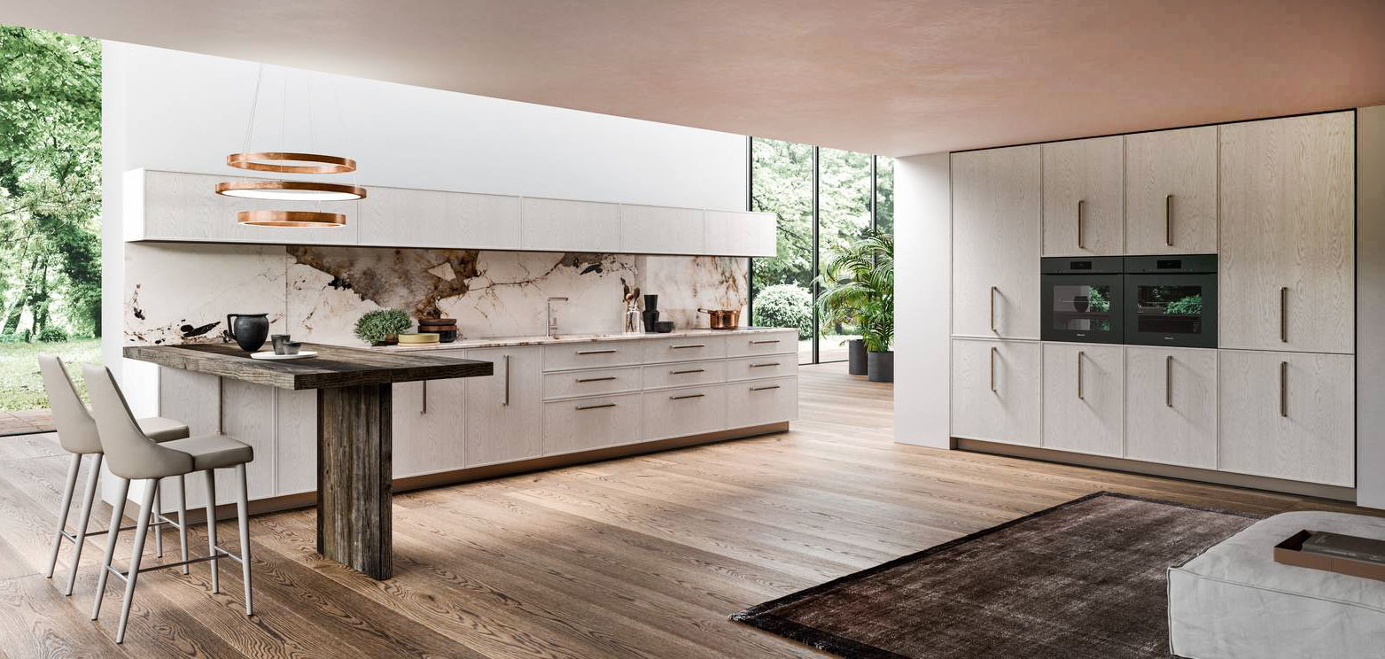 L'ampia cucina Guadalupe di ARAN si articola in una armadiatura, che include due forni e un frigorifero da incasso, e in una composizione lineare, con la zona lavello e la zona cottura, che è corredata, lateralmente, da un bancone snack di dimensioni contenute in E:wood nella finitura legno scuro. Lo schienale in pregiato marmo impreziosisce la composizione. Un modulo base da 60 cm, prezzo a partire da 612 euro + Iva. https://www.arancucine.it