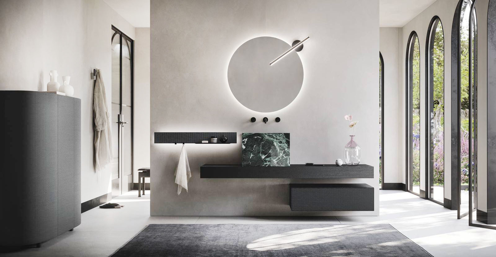 La specchiera Light Tonda dotata di luce a led perimetrale e del faretto Meridiana Nero a luce led fa parte della composizione Luxor di Arbi Arredobagno che include il piano folding in Rovere Antico Inchiostro con lavabo Zen in Laminam Verde Alpi lucido in appoggio. La base sospesa ha il fronte in intreccio Scuro e la scocca in laccato Carruba opaco; la barra Reed in alluminio Nero è corredata di una fascia in Intreccio Scuro e di luce led. La specchiera misura Ø 85 cm. Il faretto, Codice IP44, misura L 52 cm. Prezzo 360 euro. https://www.arbiarredobagno.it La specchiera Light Tonda dotata di luce a led perimetrale e del faretto Meridiana Nero a luce led fa parte della composizione Luxor di Arbi Arredobagno che include il piano folding in Rovere Antico Inchiostro con lavabo Zen in Laminam Verde Alpi lucido in appoggio. La base sospesa ha il fronte in intreccio Scuro e la scocca in laccato Carruba opaco; la barra Reed in alluminio Nero è corredata di una fascia in Intreccio Scuro e di luce led. La specchiera misura Ø 85 cm. Il faretto, Codice IP44, misura L 52 cm. Prezzo 360 euro. https://www.arbiarredobagno.it