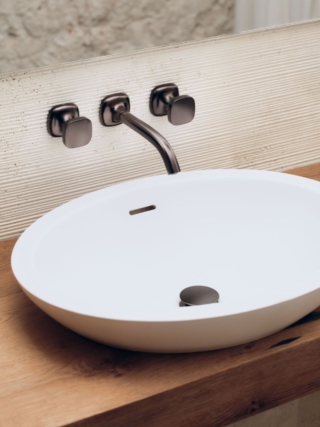 La nuova serie di rubinetterie per il bagno Coya di Dornbracht è caratterizzata dalle forme del cerchio e del quadrato che si fondono in un segno continuo e armonico, dando vita a un design che unisce con disinvoltura apparenti opposti. Un’estetica firmata Sieger Design. La serie, che va dalla rubinetteria per lavabo a quelle per vasca e doccia, fino agli accessori, è proposta in un’ampia gamma di finiture: dal Cromo alla finitura Champagne (Oro 22 kt) fino al Bronzo spazzolato. Numerose sono le possibilità di personalizzazione, come gli inserti intercambiabili delle manopole. In foto rubinetto lavabo da parete nella finitura Dark Bronze spazzolato matt. www.dornbracht.com – Fuorisalone, Dornbracht Showroom – Via Palermo 19A, Milano