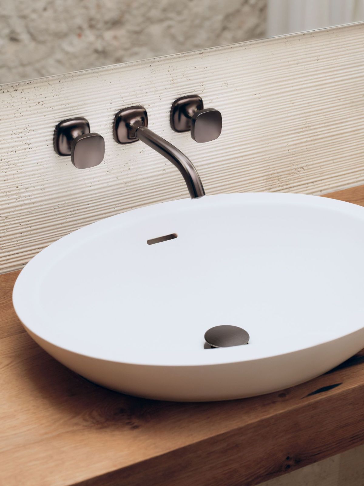 La nuova serie di rubinetterie per il bagno Coya di Dornbracht è caratterizzata dalle forme del cerchio e del quadrato che si fondono in un segno continuo e armonico, dando vita a un design che unisce con disinvoltura apparenti opposti. Un’estetica firmata Sieger Design. La serie, che va dalla rubinetteria per lavabo a quelle per vasca e doccia, fino agli accessori, è proposta in un’ampia gamma di finiture: dal Cromo alla finitura Champagne (Oro 22 kt) fino al Bronzo spazzolato. Numerose sono le possibilità di personalizzazione, come gli inserti intercambiabili delle manopole. In foto rubinetto lavabo da parete nella finitura Dark Bronze spazzolato matt. www.dornbracht.com – Fuorisalone, Dornbracht Showroom – Via Palermo 19A, Milano