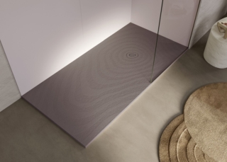 La texture “ondulata” del piatto doccia Natur Wave Forest di Acquabella ricorda
delicate increspature sabbiose che si estendono dalla griglia di drenaggio
circolare, diventando sempre più ampie e ricoprendo l’intera superficie del piatto.
È realizzato, come tutti i piatti doccia dell’azienda, in Akron®, materiale senza silice
brevettato Acquabella. Akron® unisce le qualità del poliuretano alle cariche minerali ed è
trattato su tutta la superficie con un rivestimento, anch’esso in poliuretano. È un materiale igienico, resistente a urti e shock termici e finiture ad alta definizione. www.acquabella.com – Salone del Mobile 2026, padiglione 10, Stand di Calibe A03.