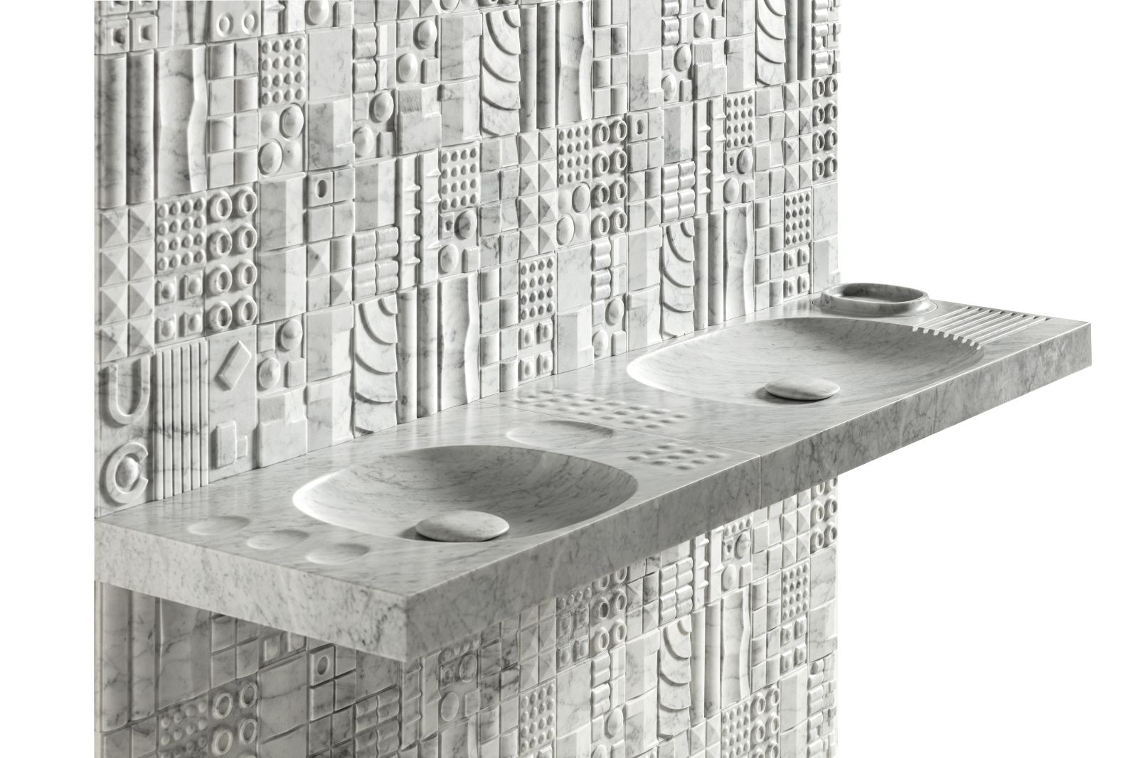 Progettato da Martinelli Venezia per Lithea il sistema-lavabo a mensola Sorgente è una micro-architettura che riporta le tracce dei paesaggi su superfici modellate da cavità, curve e rilievi. È composto da due moduli distinti in marmo Bianco Carrara. Ciascun modulo è caratterizzato da una specifica composizione di vasche scavate, elementi convessi e mini-contenitori incassati: ai lavabi si affiancano piccole sfere emergenti dalla materia, che funzionano come piani di appoggio, mentre le ciotole concave possono essere utilizzate per oggetti e accessori. I due moduli possono essere accostati tra loro, alternati, replicati oppure utilizzati singolarmente. La dimensione longitudinale corrisponde ai moduli di diverse pareti Lithea così il sistema-lavabo si allinea ai rivestimenti. Il Modulo A misura L 1,12 x P 52 x H 8 cm, quello B L 80 x P 52 x H 8 cm. Foto: NinoBartuccio. www.lithea.it – Salone del Mobile 2026, padiglione 18, Stand B08.