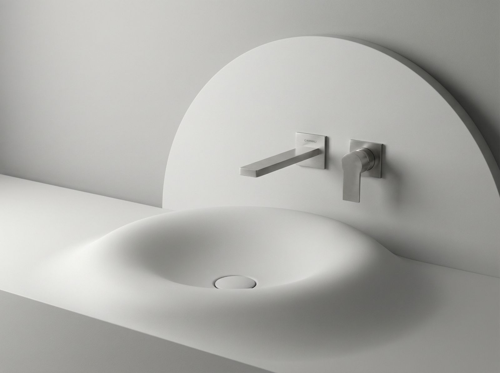 Carimali presenta la nuova versione di miscelatori a rosoni singoli per lavabo a parete della serie IlQuadro con un design che si basa sull’incontro tra due geometrie contrapposte ma complementari: il quadrato e il cerchio. La fusione dei due
elementi genera un equilibrio estetico ricercato. La separazione degli elementi di comando dalla bocca di erogazione attraverso rosoni indipendenti esalta la geometria pura di ogni componente e trasforma la rubinetteria in un elegante elemento architettonico. La collezione si presenta in un’ampia gamma di finiture che vanno dai trattamenti galvanici alle verniciature, fino alle avanzate tecnologie PVD con una resa estetica di grande impatto. Il miscelatore lavabo a parete monocomando in foto è in nickel spazzolato. www.carimali.it – Salone del Mobile 2026, padiglione 10, Stand A05.