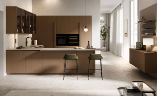 Abbina il legno e il marmo la cucina della collezione Asia di Arredo3 presentata nella versione in una composizione a golfo. Le ante lisce delle basi e delle colonne sono declinate nella finitura Cappuccino con un impiallacciato dal tono caldo e sottili venature verticali. Il piano e gli schienali sono realizzati in Abitum Marmo Venato Imperiale, un materiale ceramico che imita alla perfezione pietre e marmi, ma con performance tecniche ben più alte degli originali, pur partendo da materie prime esclusivamente naturali. https://www.arredo3.com/it - Fuorisalone, Flagship store Arredo3 Solferino – Via San Marco 1, Milano.
