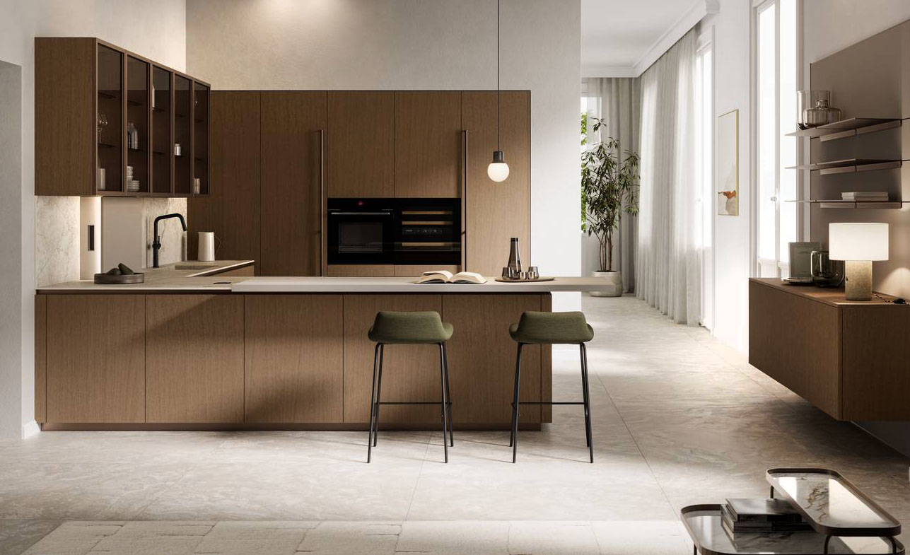 Abbina il legno e il marmo la cucina della collezione Asia di Arredo3 presentata nella versione in una composizione a golfo. Le ante lisce delle basi e delle colonne sono declinate nella finitura Cappuccino con un impiallacciato dal tono caldo e sottili venature verticali. Il piano e gli schienali sono realizzati in Abitum Marmo Venato Imperiale, un materiale ceramico che imita alla perfezione pietre e marmi, ma con performance tecniche ben più alte degli originali, pur partendo da materie prime esclusivamente naturali. https://www.arredo3.com/it - Fuorisalone, Flagship store Arredo3 Solferino – Via San Marco 1, Milano.