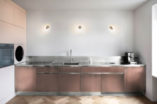 Una nuova finitura ramata galvanica per le ante della cucina lineare Atelier di Abimis: è ottenuta tramite la lavorazione che combina le calde sfumature del bronzo e del rame, trasformando l’acciaio Inox in un elemento vivo e sofisticato. La micro-spazzolatura orientata genera sulla superficie sottili linee parallele che arricchiscono l’esperienza tattile e visiva. Ogni progetto può essere personalizzato in modo “sartoriale” secondo esigenze e gusto estetico. https://abimis.com - EuroCucina 2026, padiglione 04, Stand C15.