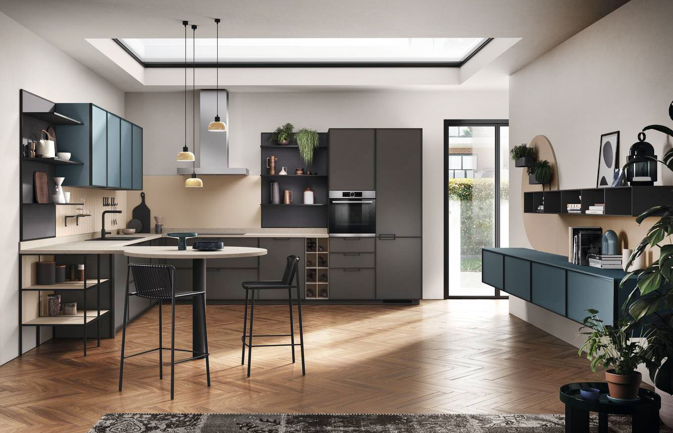 La composizione Jeometrica di Scavolini si apre completamente sulla zona giorno che è arredata con una serie di basi sospese in laccato opaco Verde Ottanio come i pensili. La cucina ad angolo ha le basi e le colonne in Laccato opaco Grigio Ferro ed è corredata di un tavolo/penisola con il piano in Quarz Motley. Prezzo su richiesta. https://www.scavolini.com