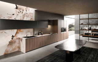 Uno sviluppo lineare per la composizione Lab13 di ARAN Cucine che ha le ante Rigoletto Plus, delle basi e delle colonne, realizzate in noce americano naturale e impreziosite da scanalature verticali e regolari. Il top in gres color magellano si estende sulla parete come un murales decorativo; i pensili a sviluppo orizzontale, con apertura a ribalta, sono in laccato metallo liquido piombo. La libreria Watch-it, che separa la zona operativa dal soggiorno, ha i ripiani in legno e la struttura in metallo nero. Un modulo base da 60 cm, prezzo a partire da 605 euro + Iva. https://www.arancucine.it