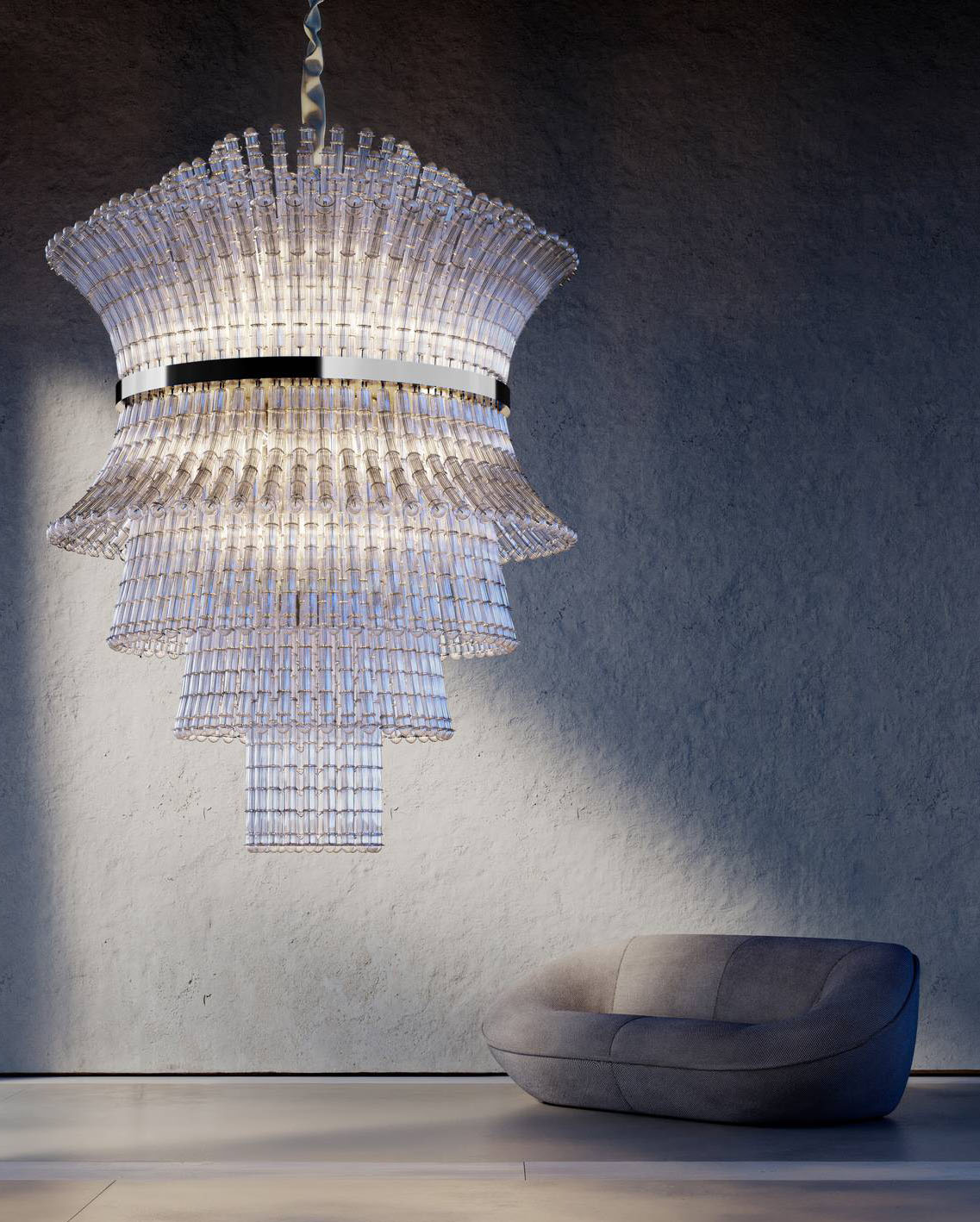 Scenografico e scultoreo il lampadario chandelier Étoile de iDOGI: è composto da 5.000 bossole in vetro artistico, trasparente e sabbiato, impreziosite dalla trama Rigadin, un' antica lavorazione di Murano, che si sviluppano attorno al lungo e affusolato elemento centrale  con una silhouette a clessidra che si apre a raggiera verso l’alto. https://www.idogi.com - Salone del mobile 2026, padiglione 13, Stand C20.