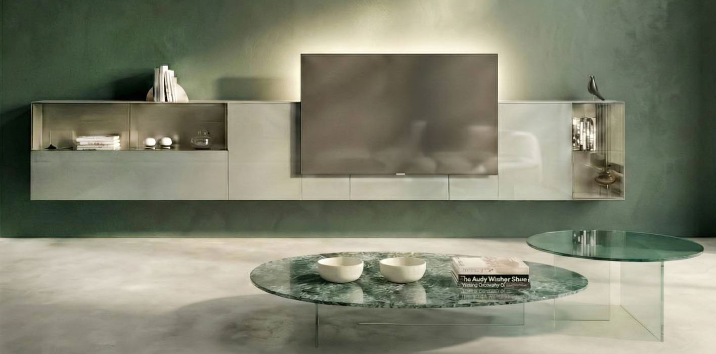 La parete attrezzata 36e8 Cinema di Lago fonde tecnologia e design, infatti il televisore diventa fulcro della composizione in vetro lucido Foresta per un'esperienza immersiva. Il modulo retrostante accoglie un sistema di illuminazione integrato che amplifica la profondità percettiva e valorizza l'esperienza di visione. Inoltre, si integra con Lago Invisible Sound, un sistema audio ad alta qualità che diffonde il suono del televisore o la musica - connettendosi allo smartphone - direttamente dal mobile, trasformando l'arredo in dispositivo acustico.  https://www.lago.it - Salone del mobile 2026, padiglione 24, Stand D06, D08.