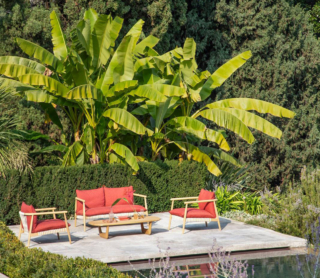 Le sedute per l'esterno della collezione Karin Outdoor di Desiree fondono tradizione artigianale e  sensibilità contemporanea: sono realizzate in legno di iroko naturale abbinata a fettuccia di poliestere lavorata a mano. I cuscini con inserti in poliuretano sono rivestiti da tele idrorepellenti completamente sfoderabili. https://www.desiree.com - Salone del mobile 2026, padiglione 09, Stand L09, M06.