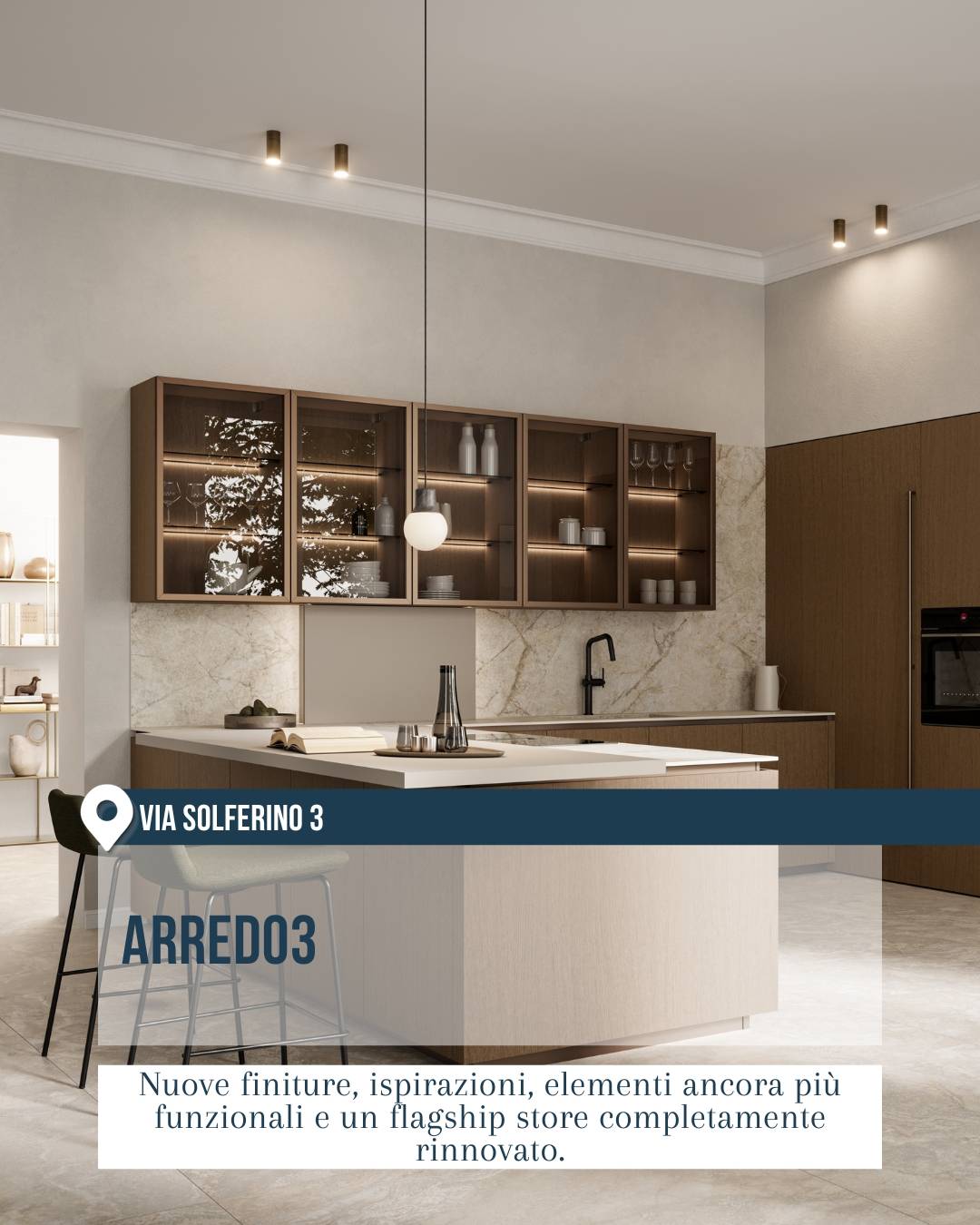 Arredo3 in via Solferino 3 a Milano durante il Fuorisalone 2026. Cucina di design con isola centrale chiara, mobili in legno, vetrine illuminate e finiture calde, in uno showroom rinnovato all’insegna di funzionalità ed eleganza.
