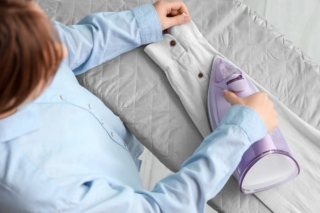 Woman,Ironing,Sleeve,Of,Shirt,On,Board,At,Home,,Top