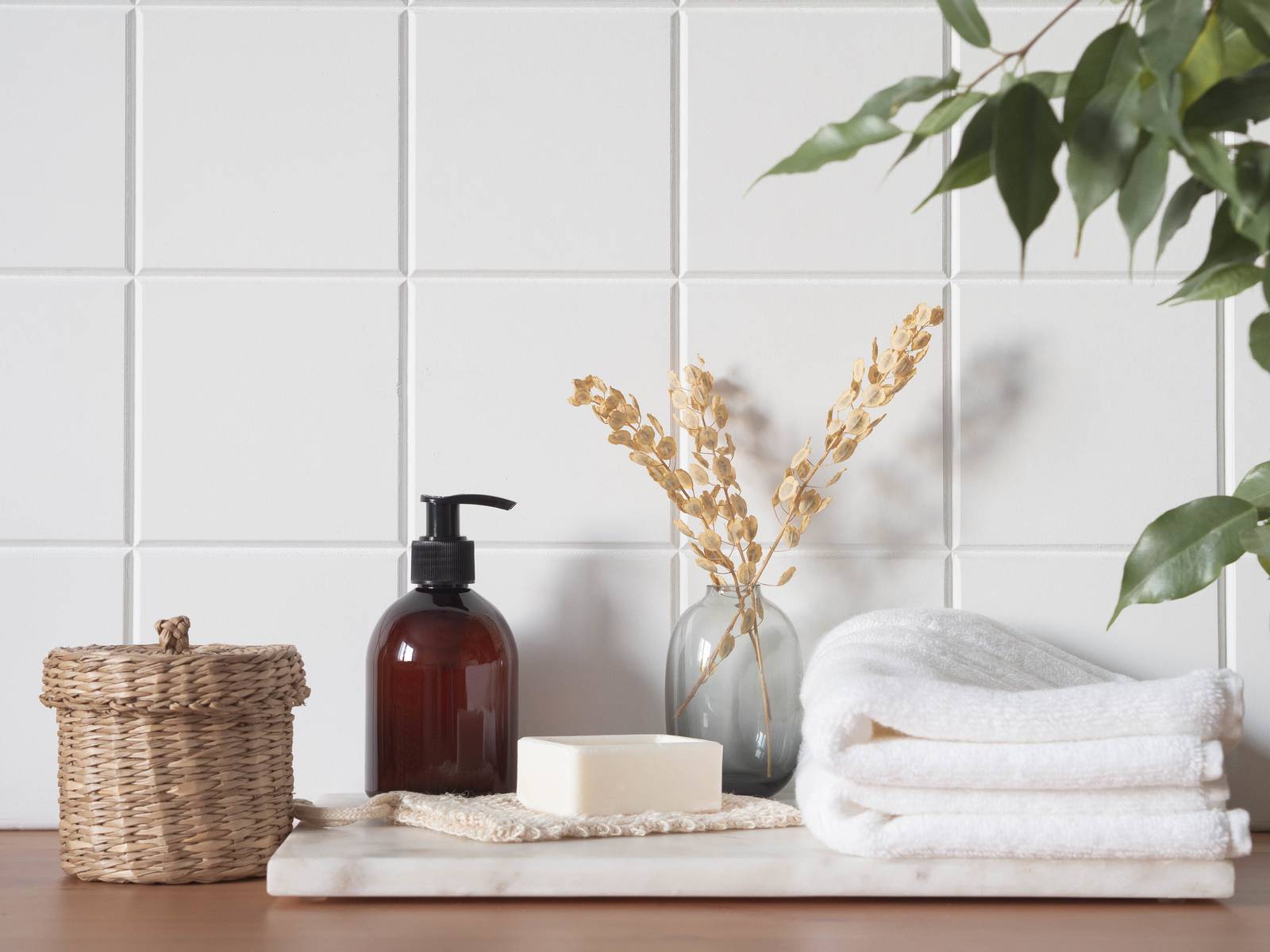 White bath background front view with cosmetic bottle, bath accessories on wood shelf and wall tiles. Copy space