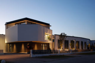 La palazzina di notte: l'illuminazione esterna esalta i volumi aggettanti e lo sbalzo del piano superiore.