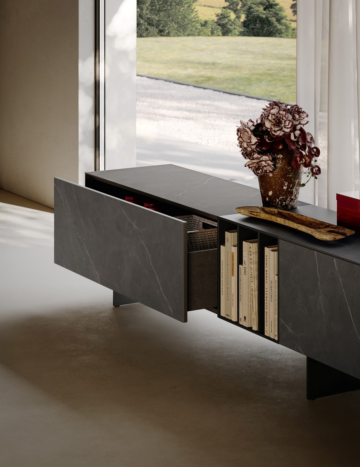 La madia Caccaro Wallover usa un linguaggio essenziale e architettonico per integrarsi negli spazi living contemporanei. Slanciata dal piede 180, la composizione alterna il rigore dei volumi pieni alla leggerezza visiva dei vani libreria, creando un equilibrio tra funzione ed estetica. I cassetti con chiusura ammortizzata assicurano praticità d’uso, mentre le finiture kera pietra grey e laccato opaco basalto contribuiscono a definire un’immagine sofisticata e materica. Misure: L 300 × P 45,5 × H 60 cm. Prezzo: 3.320 euro + IVA.
